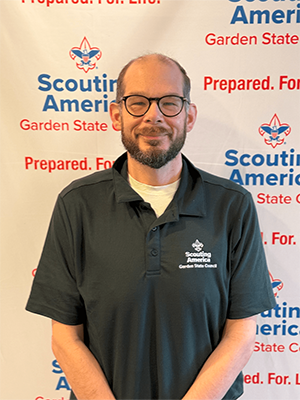 Preston I. smiling in a Garden State Council polo shirt in front of a Scouting America backdrop.