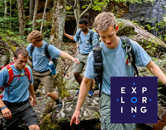 Exploring participants hiking together along a rocky wooded trail, with the Exploring logo displayed in the foreground.