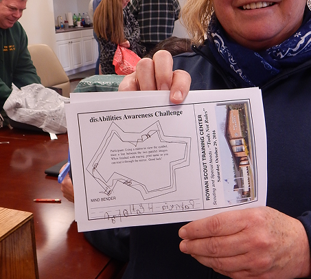 Participant holding a completed disAbilities Awareness Challenge activity sheet during a Scouting training session.