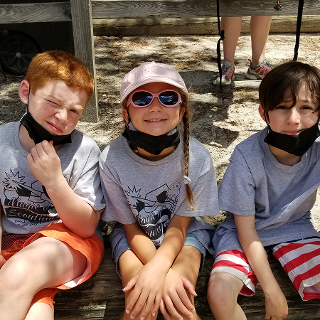 Three young Scouts sitting together on a bench during summer camp.