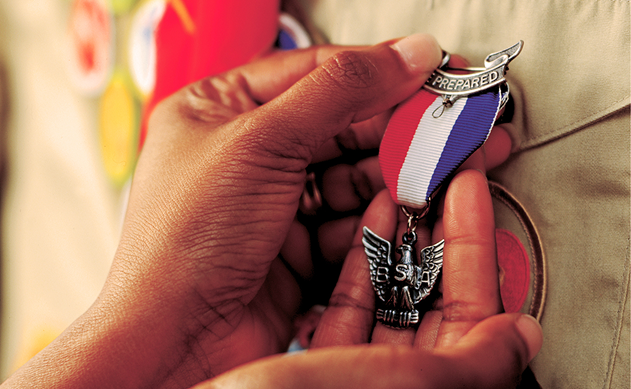 Close-up of an Eagle Scout medal being pinned onto a Scout uniform.