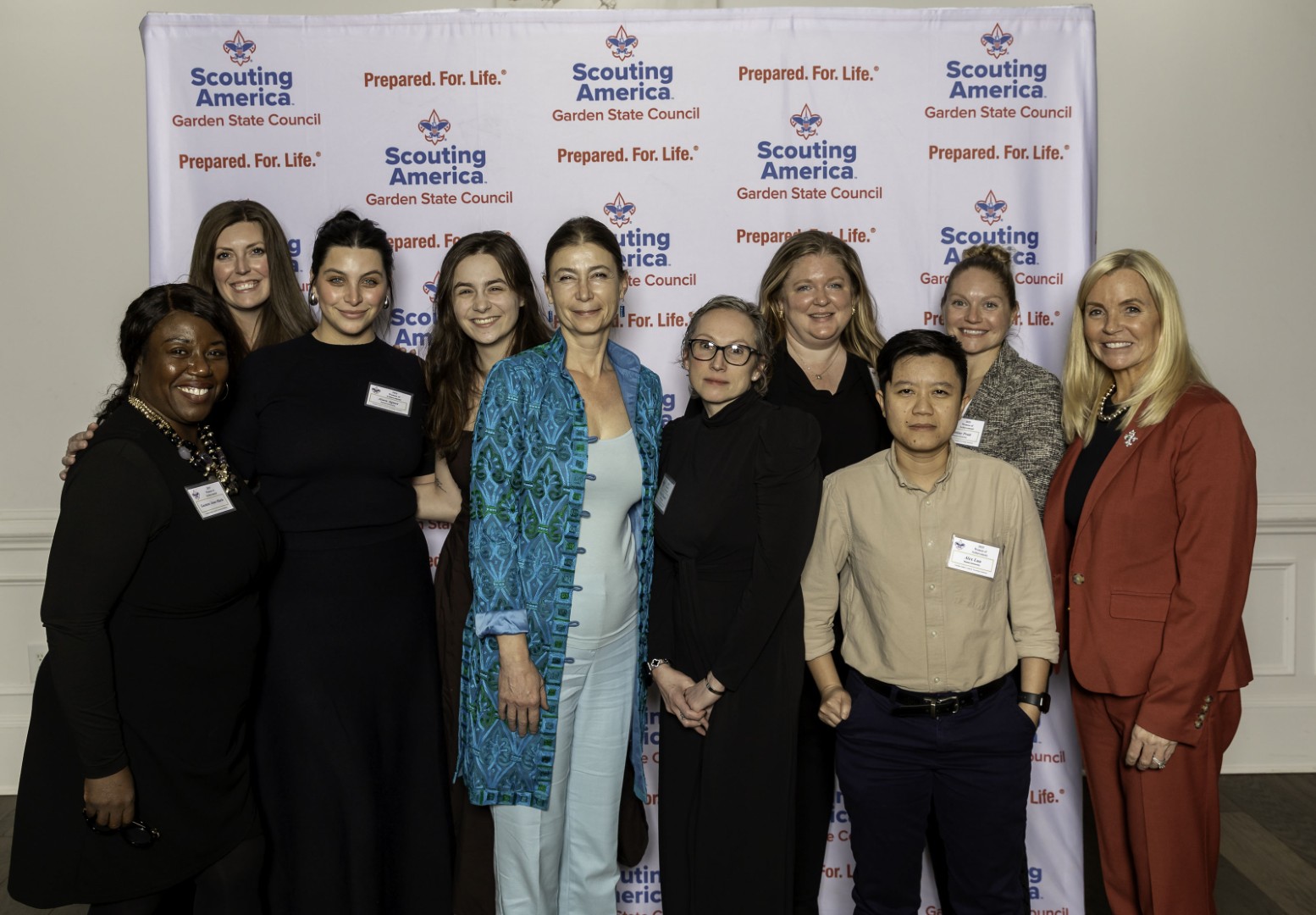 Group of attendees posing together in front of a Garden State Council Scouting America backdrop at the Women of Achievement event.