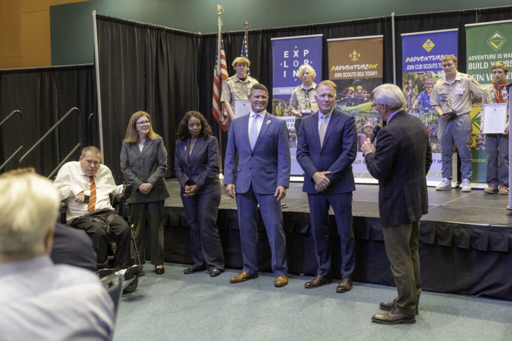 Community leaders being recognized during a Garden State Council ceremony as Scouts stand on stage behind them.