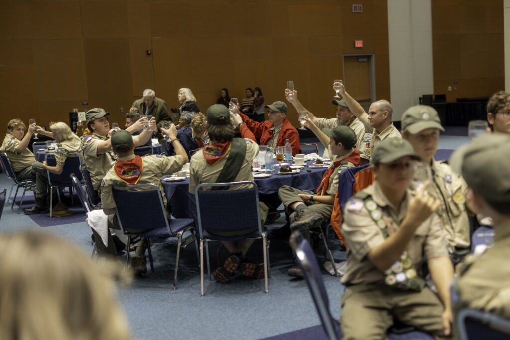 Scouts and adult leaders raising their glasses together during a Scouting recognition banquet.