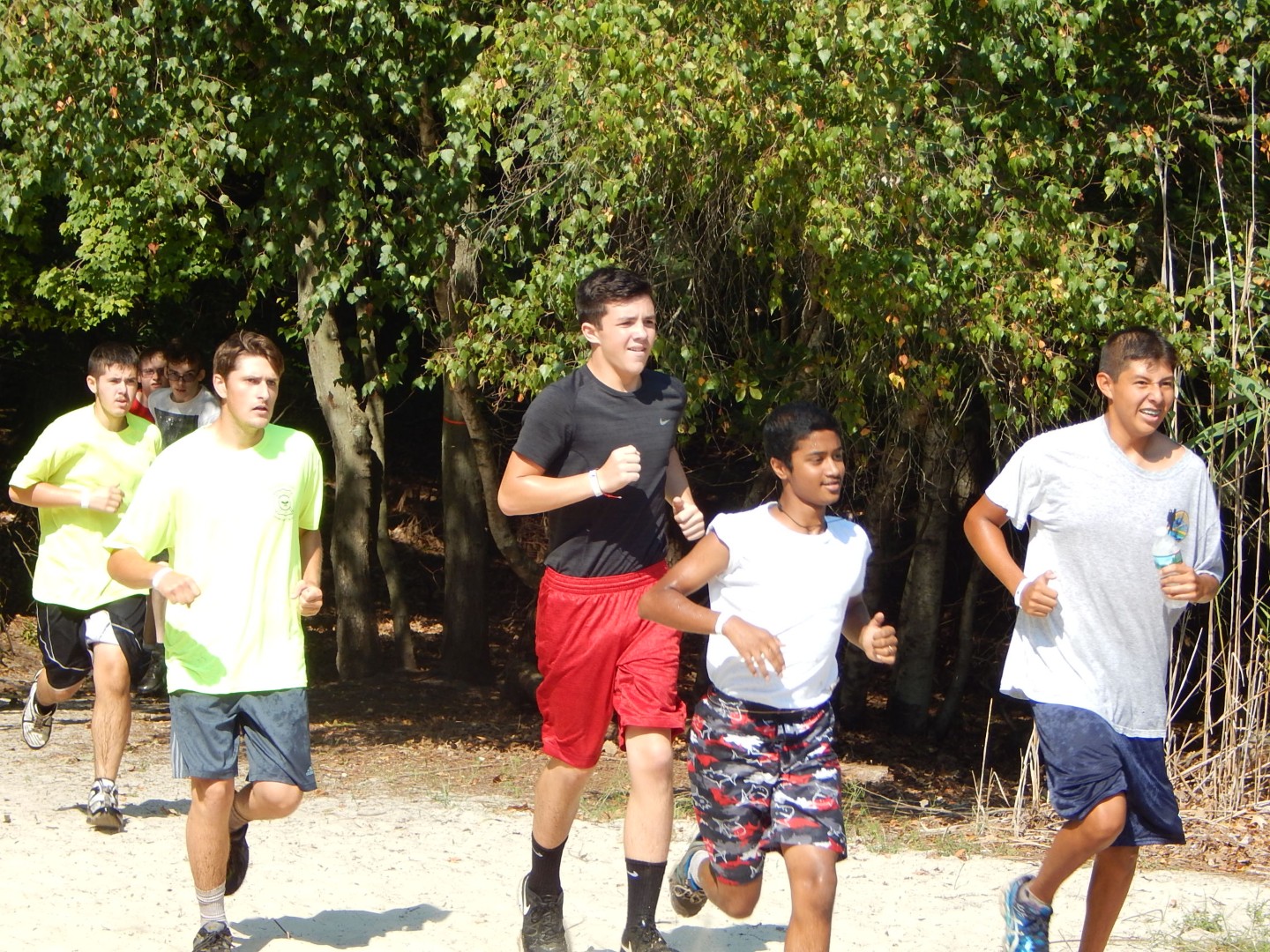 Scouts running together on a wooded outdoor trail.