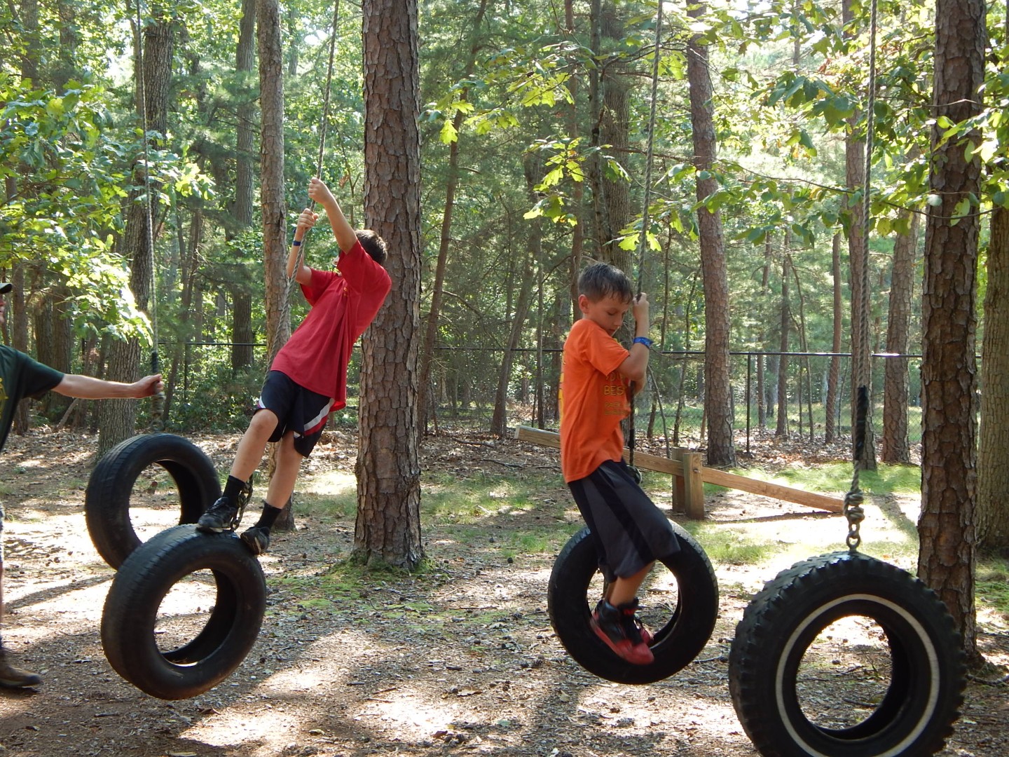 Two Scouts navigating a hanging tire obstacle course in a wooded area.