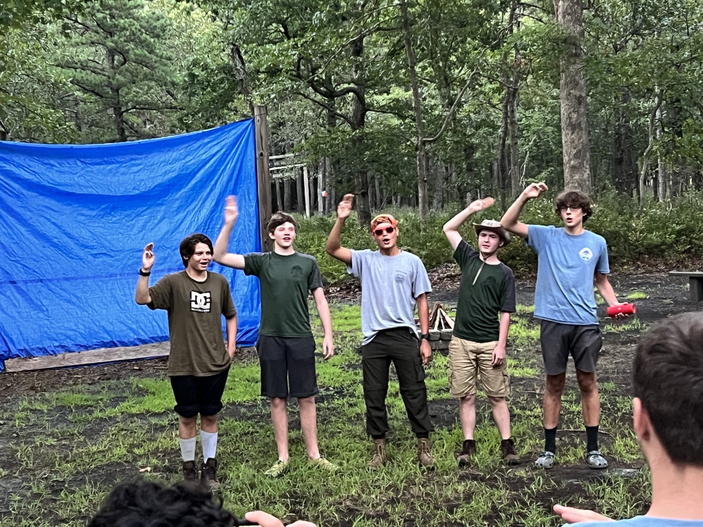 Five Scouts raising their hands together during an outdoor group activity at 2023 Trek Camp.