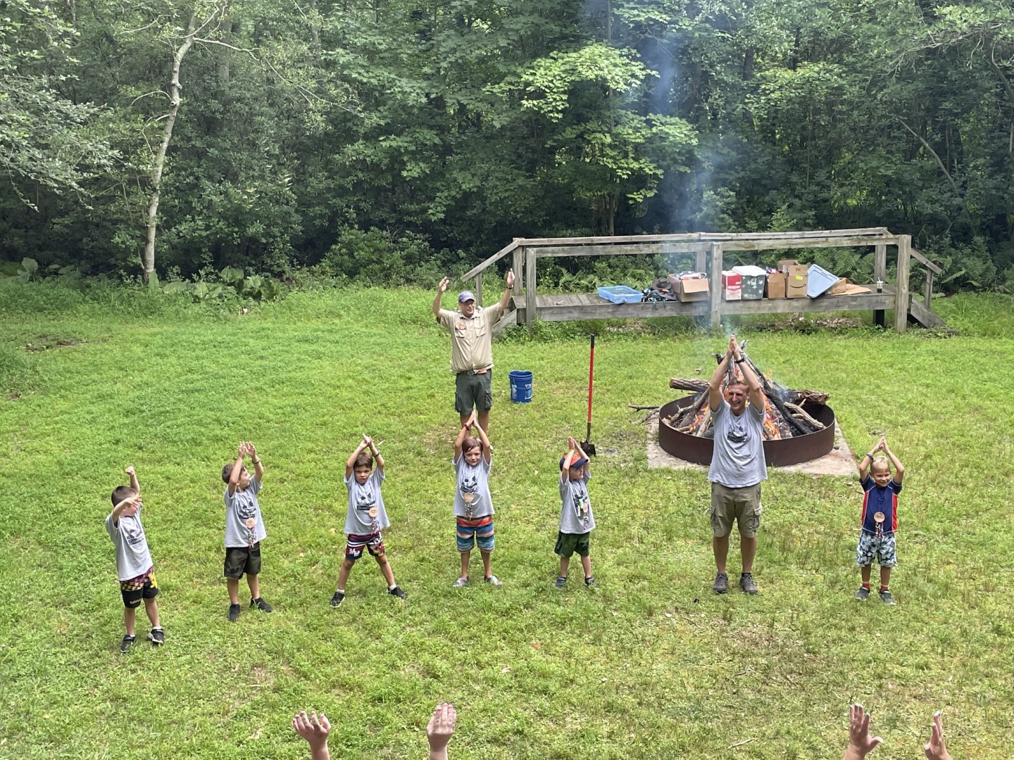 Cub Scouts and adult leaders participating in a group activity beside a campfire at the 2022 Magic of Scouting Day Camp in Pine Hill.