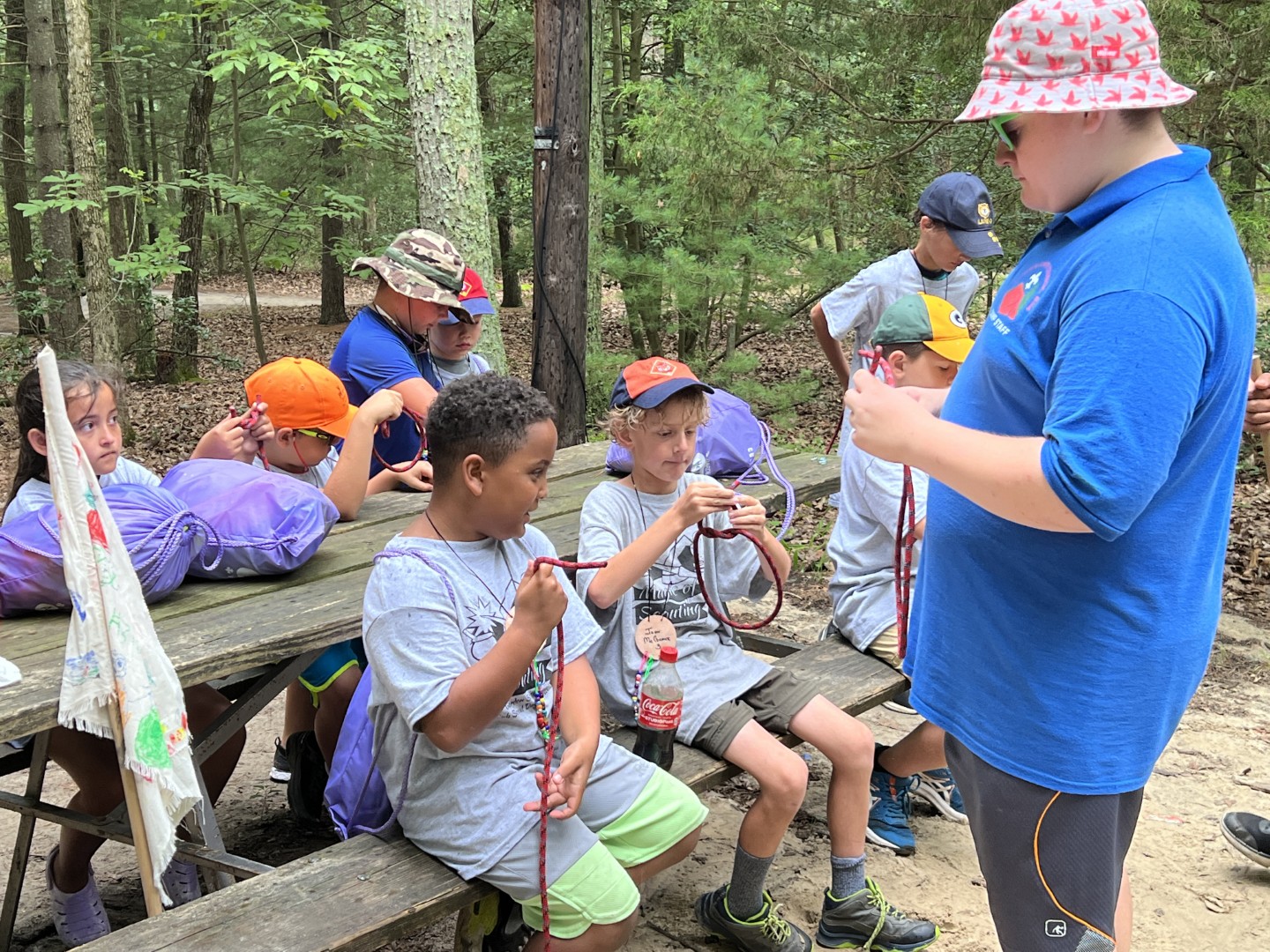Cub Scouts practicing knot tying together at a picnic table during the 2022 Magic of Scouting Day Camp in Pine Hill.