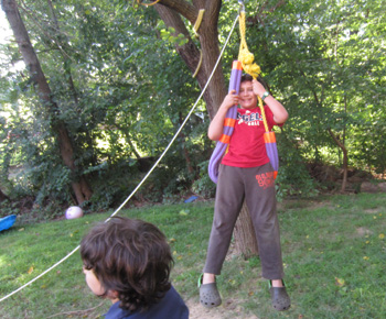 Scout pulling on a rope during an outdoor activity in a wooded area.